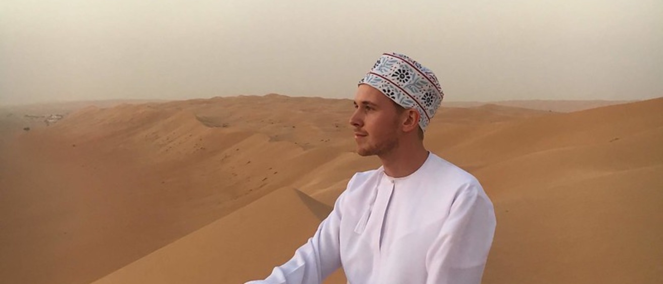 Alex in Oman wearing traditional dress in desert