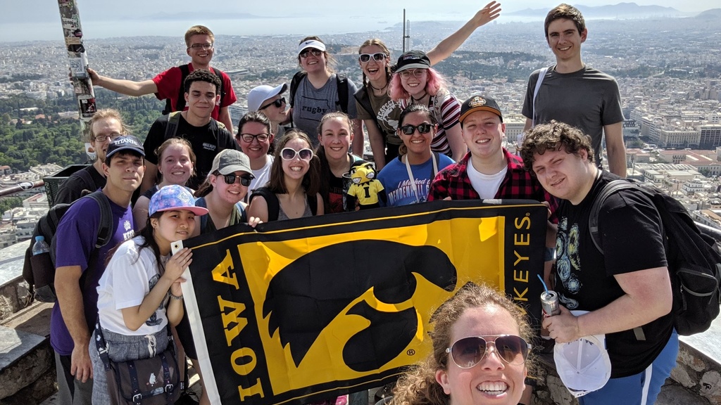 Deb Trusty and Students in Greece with Hawkeye flag