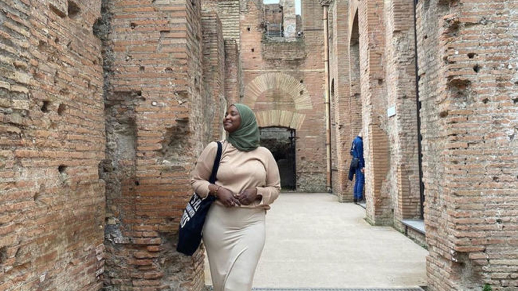 Sauda Abdullahi walking through stone buildings in Europe