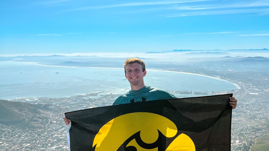 Alex Hefel with scenic background holding Hawkeye flag