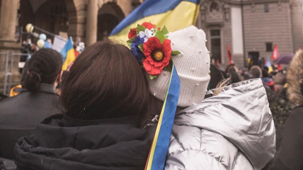 two people hug while holding a Ukrainian flag