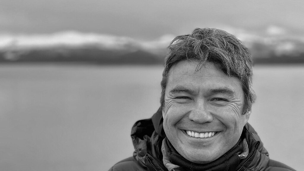 man smiling in front of glacier