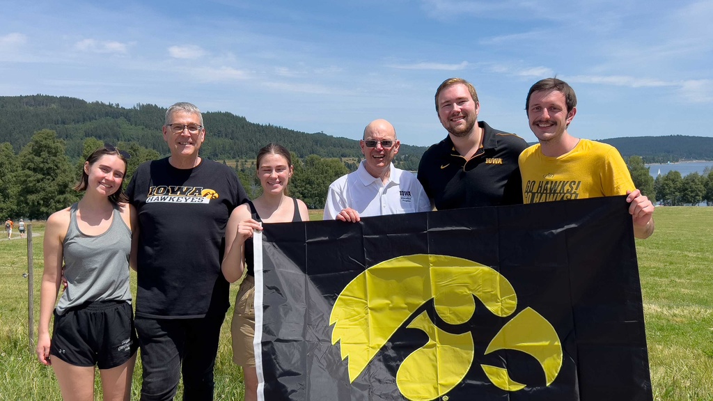 Russ Ganim with others holding Iowa flag in mountains in Germany