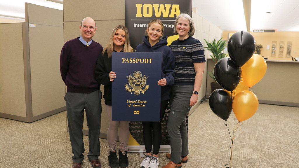 Russ Ganim, Winnie and Vivian Ferrell holding giant passport and Candice Stevens in front of Iowa sign