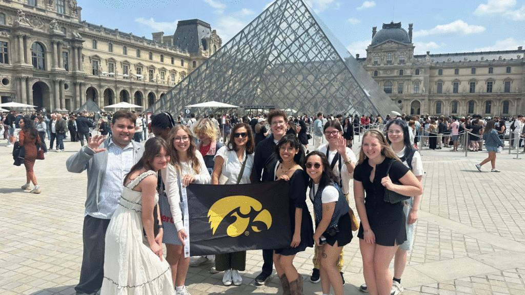 students holding Iowa flag in front of the Louvre pyramid