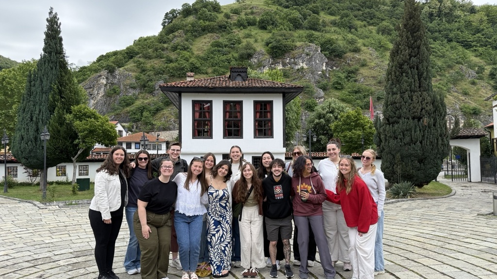 University of Iowa graduate students and professors, including Charlotte Hilker, pose in front of the Albanian League of Prizren.