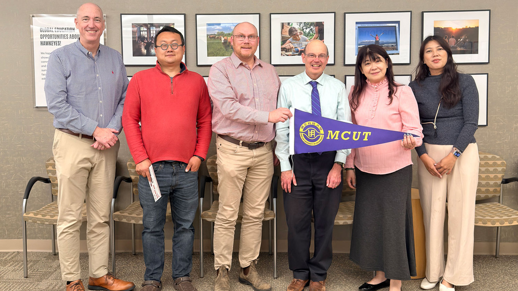 Russ Ganim with visitors from Ming Chi University of Technology in front of sign "Connecting Iowa with the World and the World with Iowa"