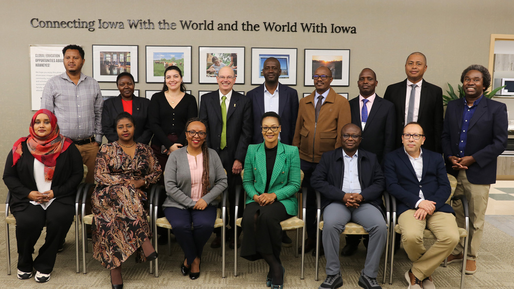 Group of visitors seated and standing in International Programs office