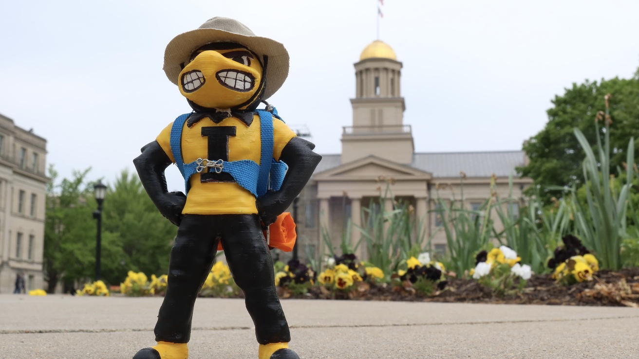 Herky dressed in hiking gear in front of old capitol